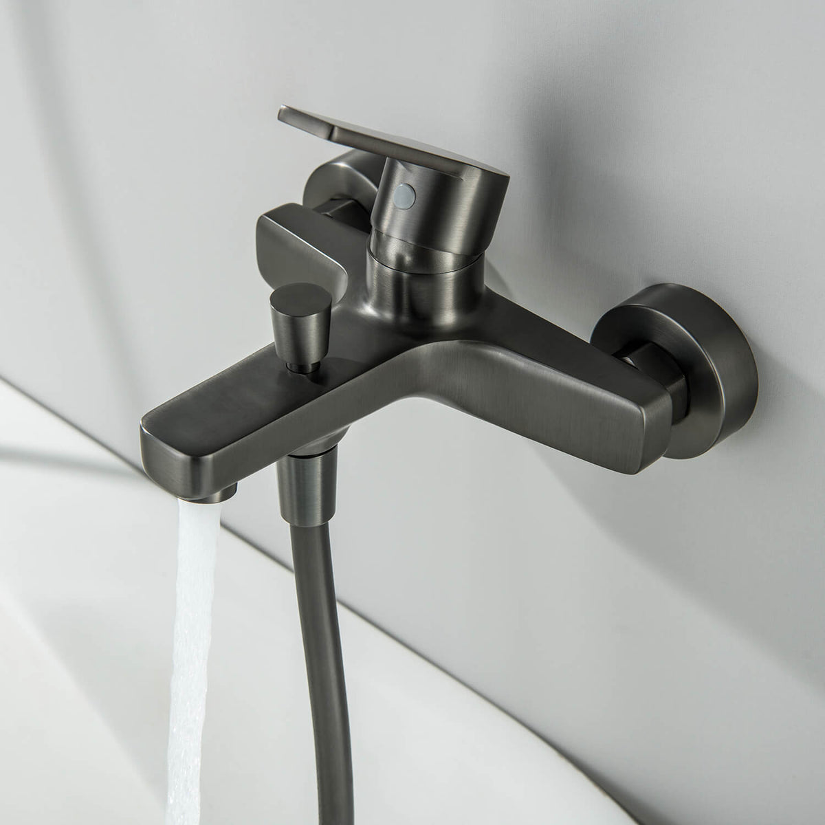 Aquavit Sense brushed gunmetal bath shower mixer with water flowing from the spout