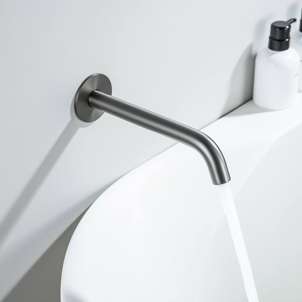 Aquavit Circular brushed gunmetal wall-mounted bath spout installed above a modern bathtub