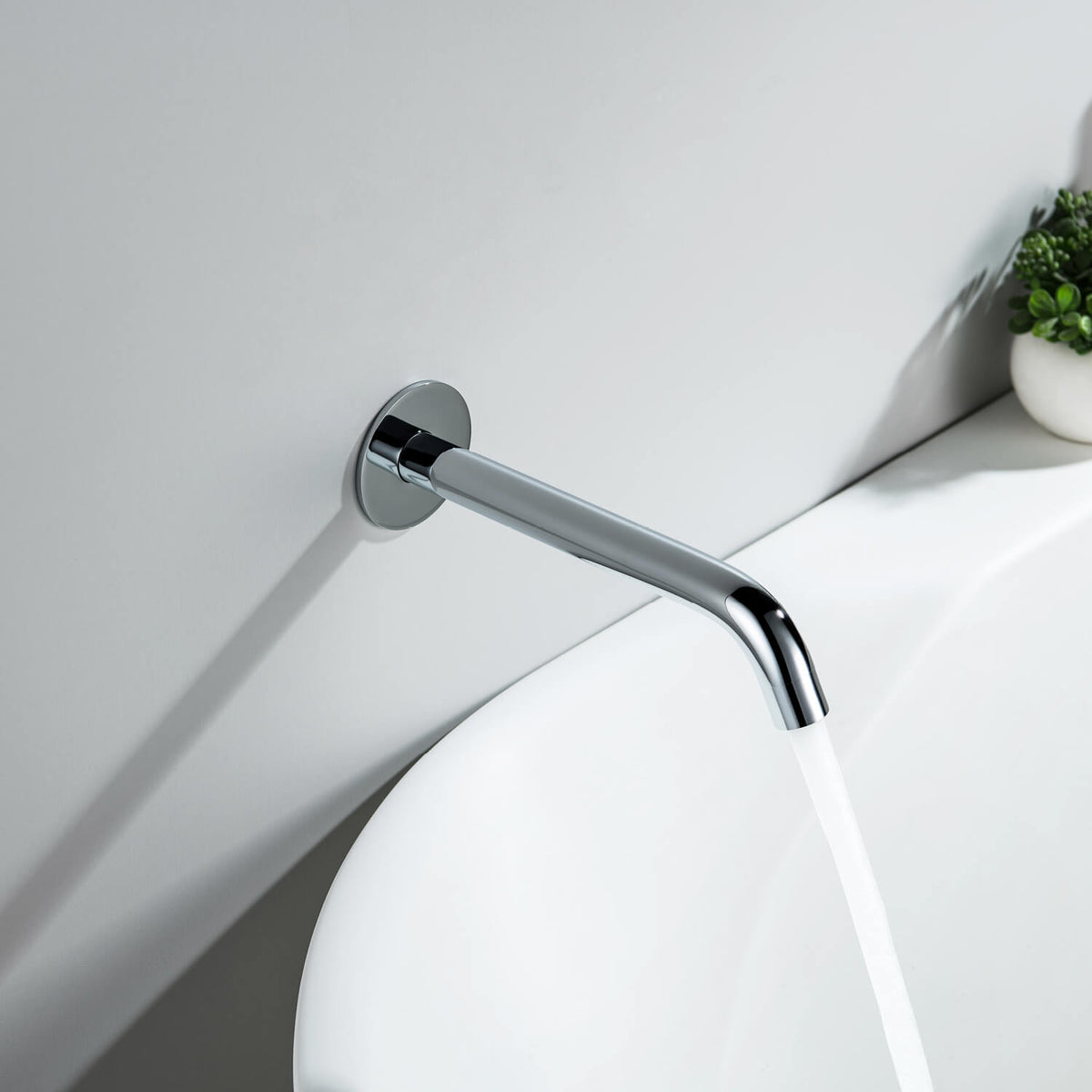 Aquavit Circular chrome bath spout delivering water into a contemporary bathtub